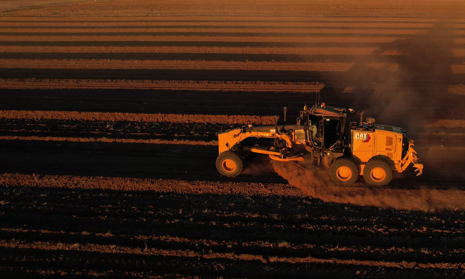 Grader in field during sunset